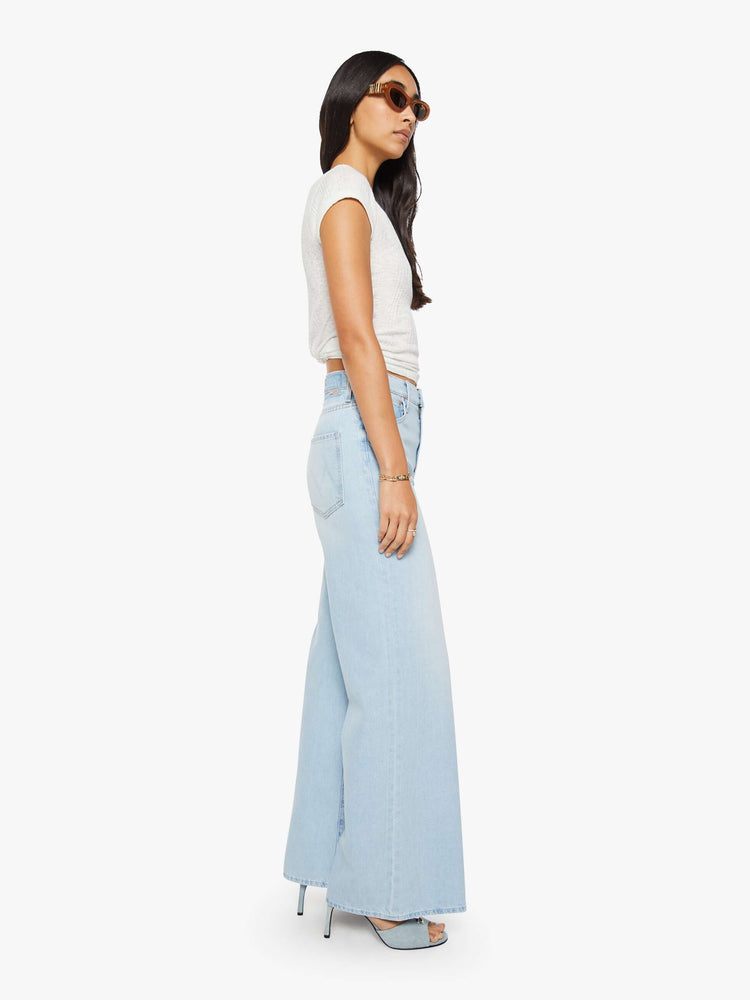 Side view of a woman in a light blue wide-leg jeans feature a high rise with a slightly dropped crotch, zip fly, low-set back pockets and a 31-inch inseam.