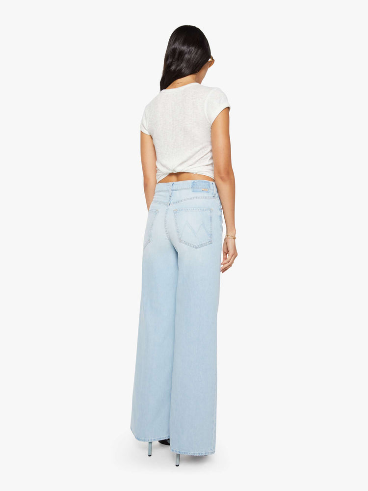 Back view of a woman in a light blue wide-leg jeans feature a high rise with a slightly dropped crotch, zip fly, low-set back pockets and a 31-inch inseam.