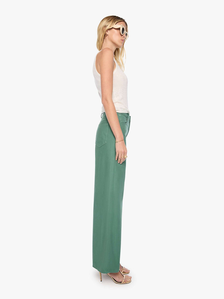Side view of a woman in olive green pant wide legs feature a high rise with a slightly dropped crotch, zip fly, low-set back pockets and a 31-inch inseam with a clean hem.