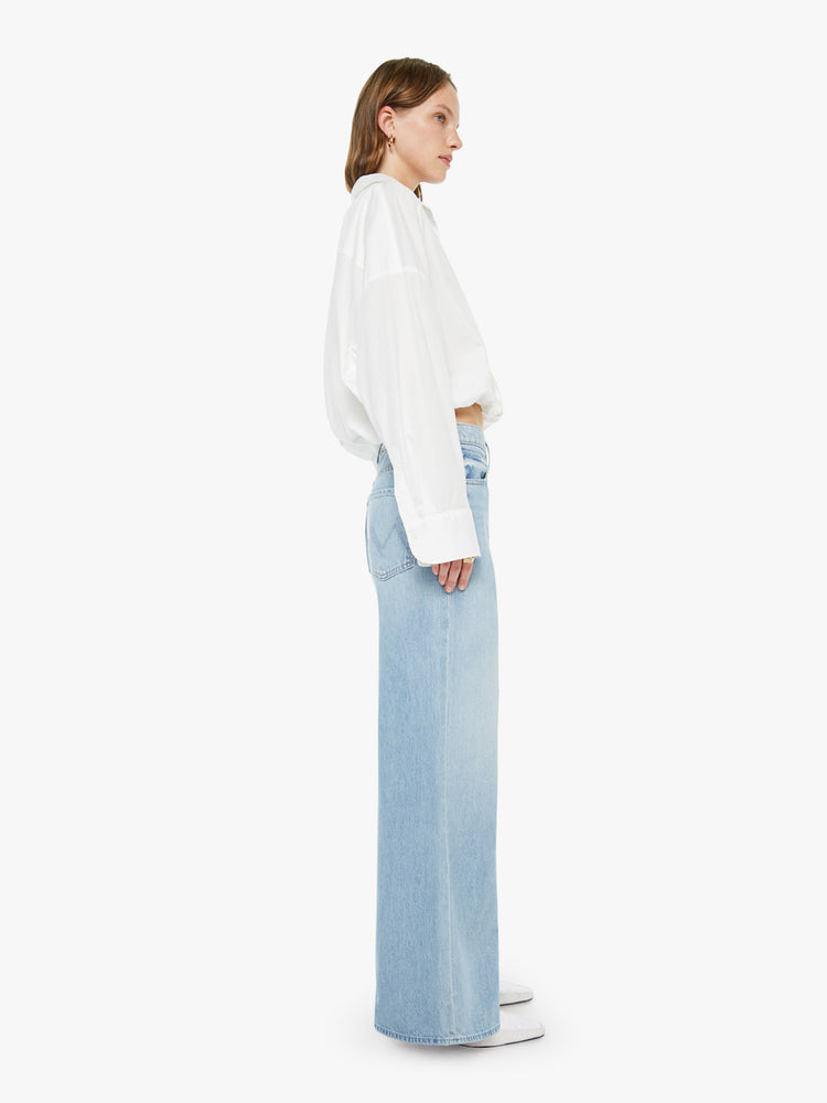 Side view of a woman in a light blue wide-leg jeans feature a high rise with a slightly dropped crotch, zip fly, low-set back pockets and a 31-inch inseam.