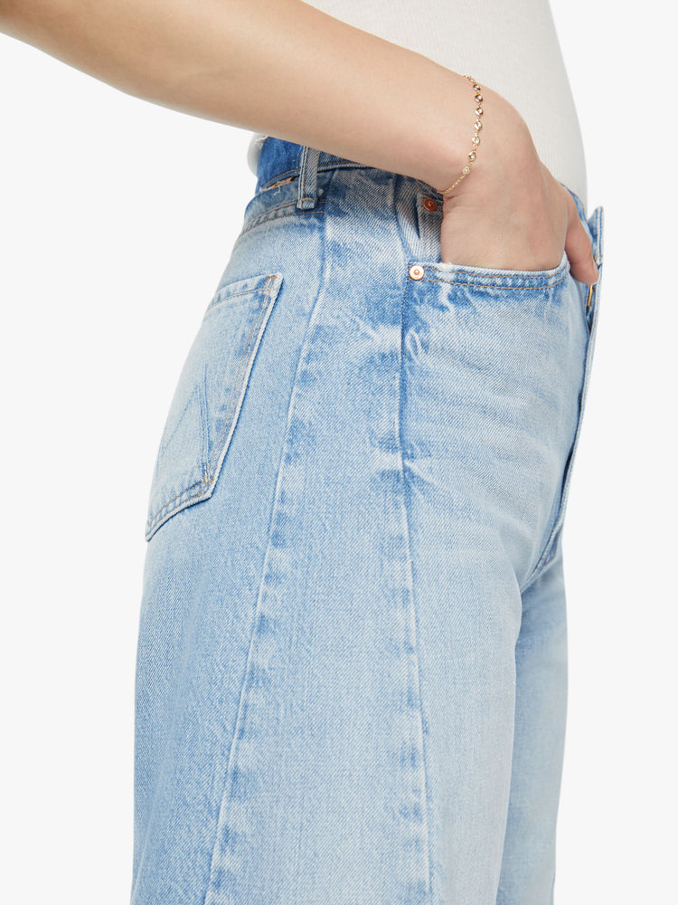 Waist close up view of a woman super high-waisted jean with a wide, curved leg, an ankle-length inseam and a clean hem in a light blue wash.