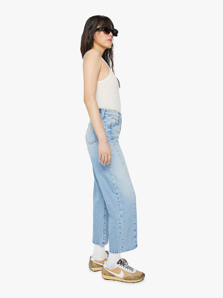 Side view of a woman super high-waisted jean with a wide, curved leg, an ankle-length inseam and a clean hem in a light blue wash.