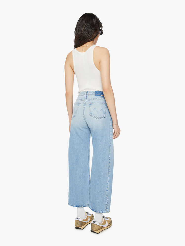 Back view of a woman super high-waisted jean with a wide, curved leg, an ankle-length inseam and a clean hem in a light blue wash.