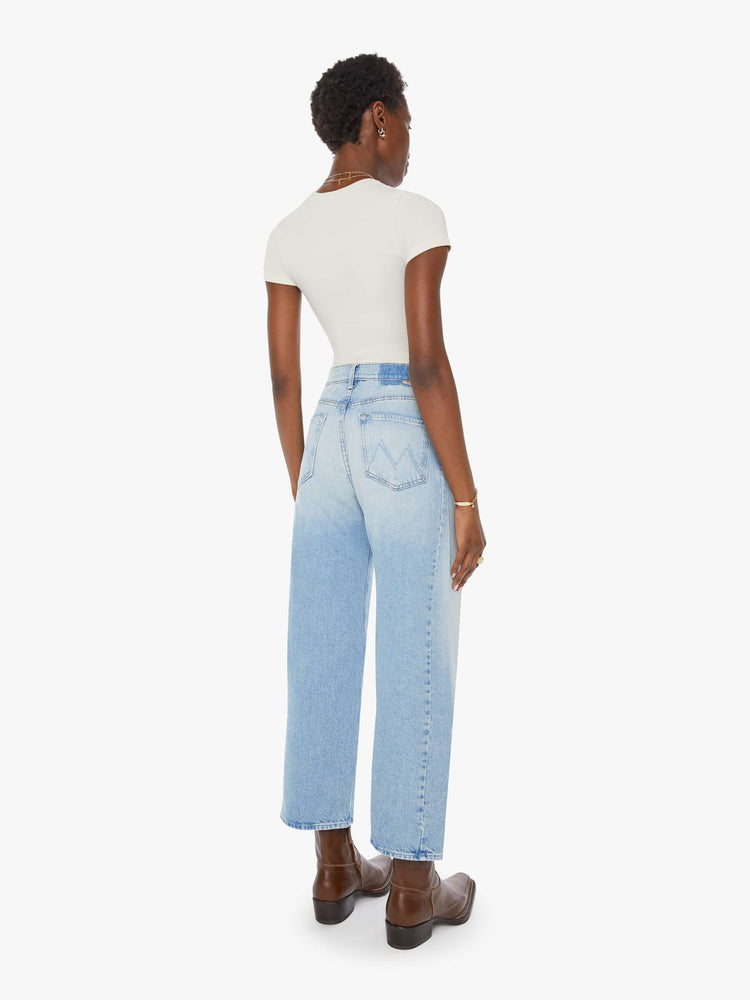 Back view of a woman super high-waisted jean with a wide, curved leg, an ankle-length inseam and a clean hem in a light blue wash.