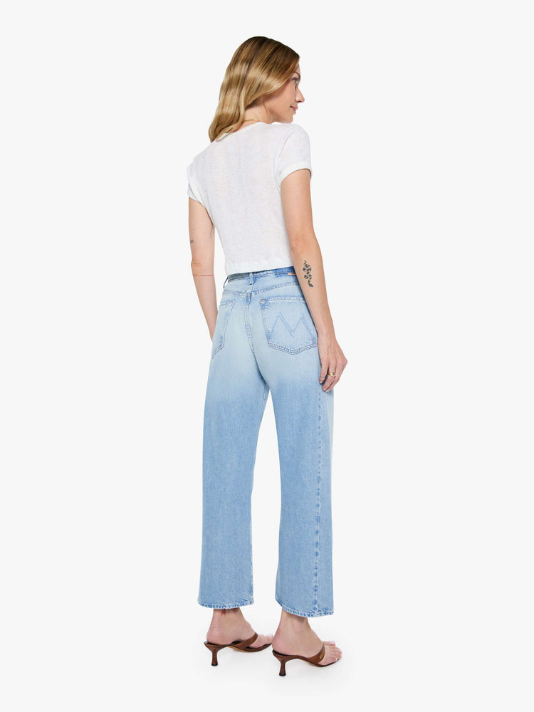 Back view of a woman super high-waisted jean with a wide, curved leg, an ankle-length inseam and a clean hem in a light blue wash.