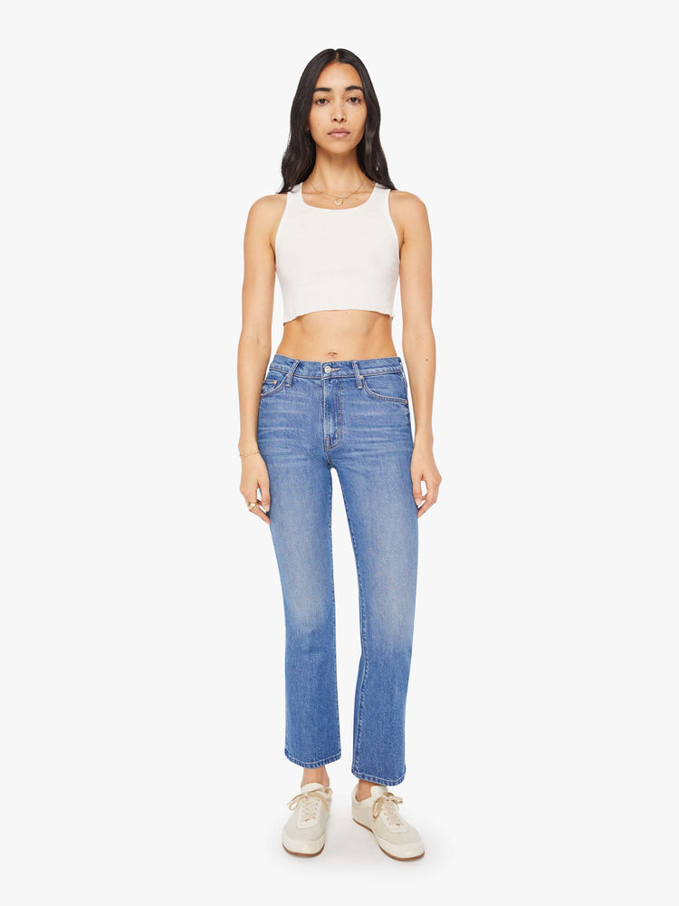 Front view of a woman in a med blue narrow flare jeans with a mid rise and a 28.25-inch inseam with a clean hem.