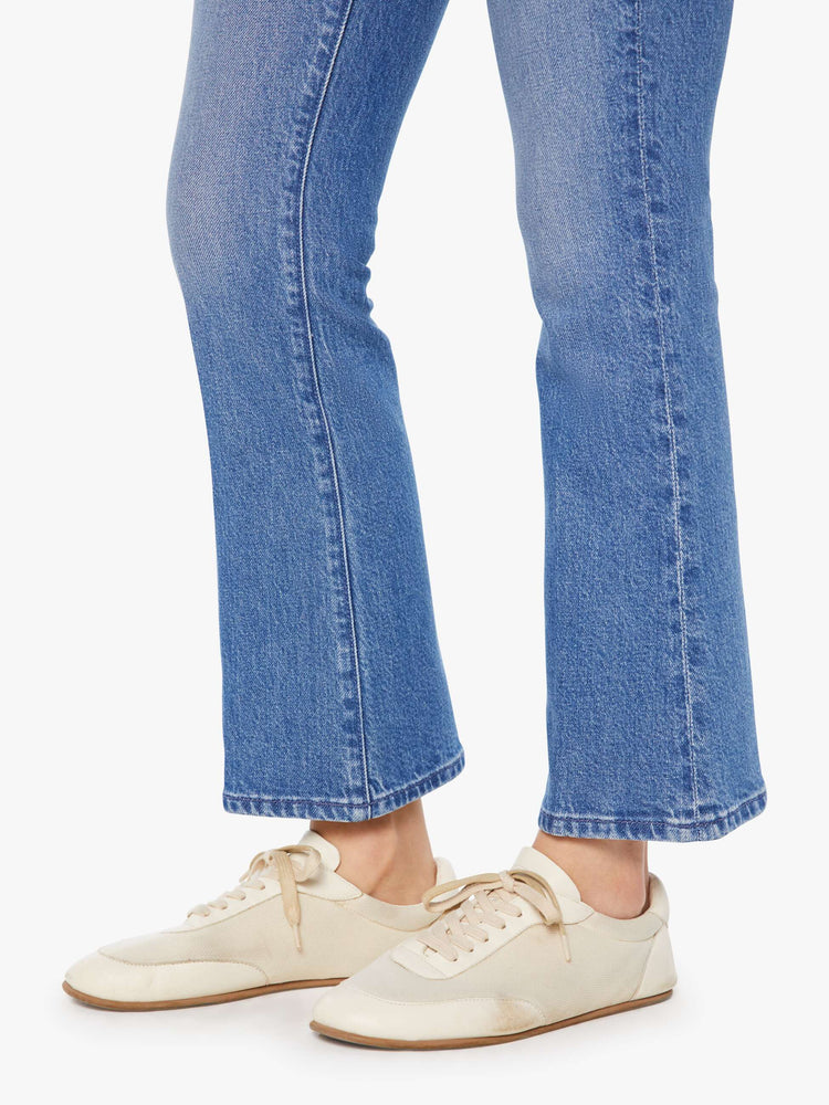 Hem view of a woman in a med blue narrow flare jeans with a mid rise and a 28.25-inch inseam with a clean hem.