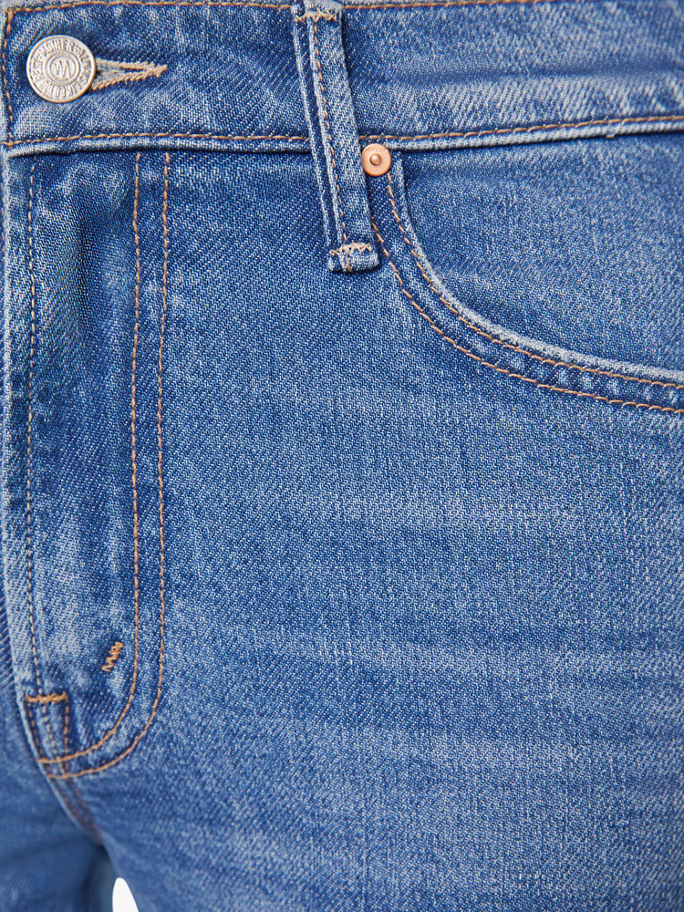 Swatch view of a woman in a med blue narrow flare jeans with a mid rise and a 28.25-inch inseam with a clean hem.