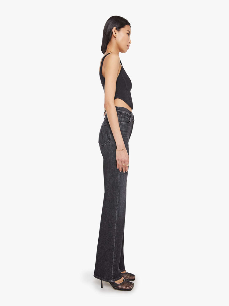 Side view of a woman in a washed black high-waisted jeans with a wide straight leg, zip fly and a long 34-inch inseam with a clean hem.