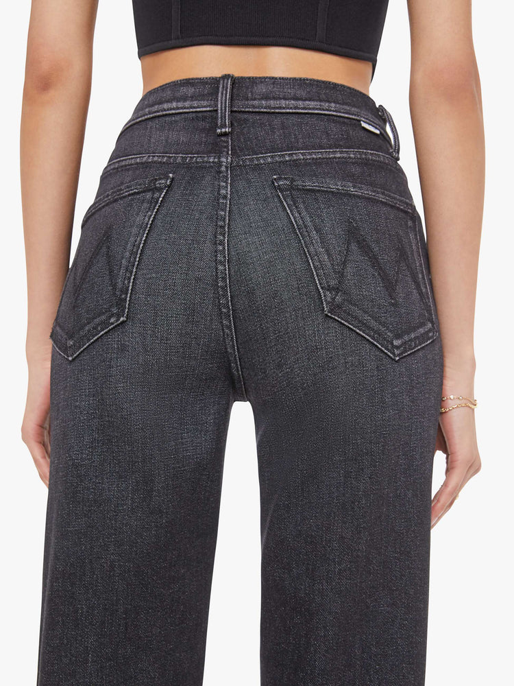 Close up view of a woman in a washed black high-waisted jeans with a wide straight leg, zip fly and a long 34-inch inseam with a clean hem.