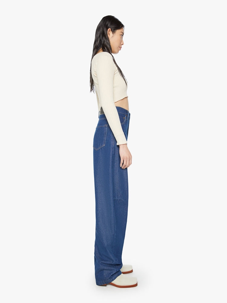 Side view of a woman super high-rise jeans are designed with loose fit and a tapered leg with a long 34-inch inseam that stacks at the ankle in a dark blue wash.