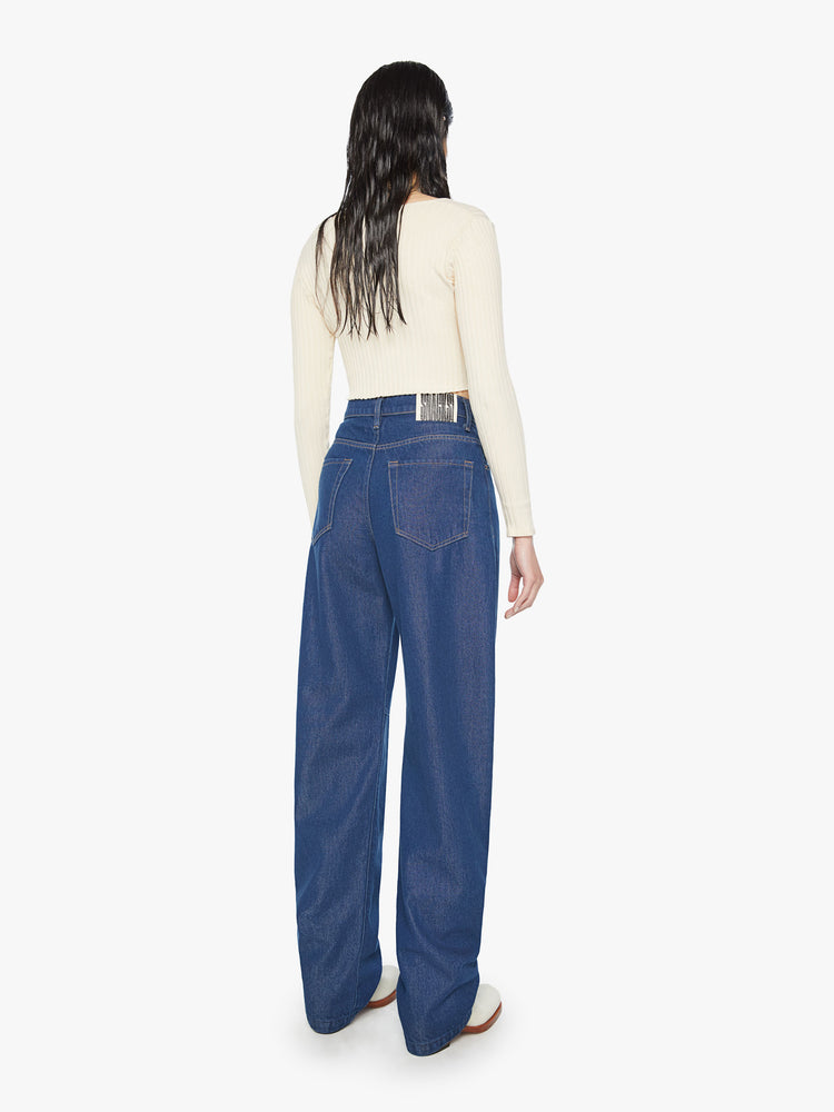 Back view of a woman super high-rise jeans are designed with loose fit and a tapered leg with a long 34-inch inseam that stacks at the ankle in a dark blue wash.
