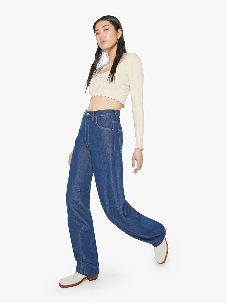 Walking view of a woman super high-rise jeans are designed with loose fit and a tapered leg with a long 34-inch inseam that stacks at the ankle in a dark blue wash.