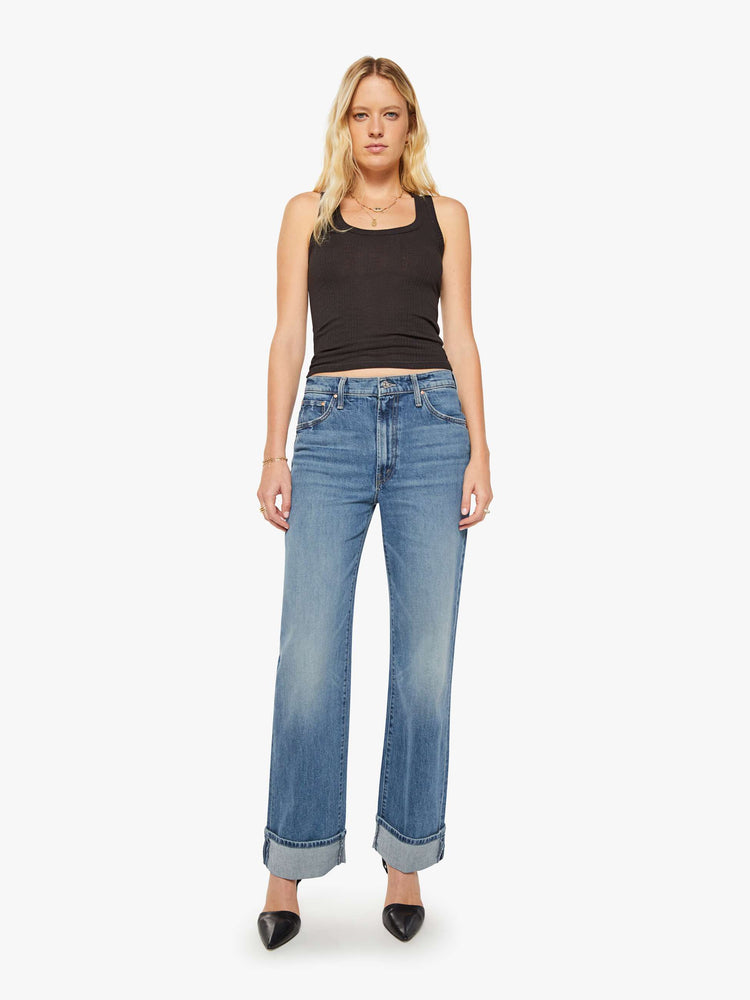 Front view of woman in a mid blue wash jean  designed to sit lower on the hips with a loose straight leg and a 31-inch inseam with a clean cuffed hem.