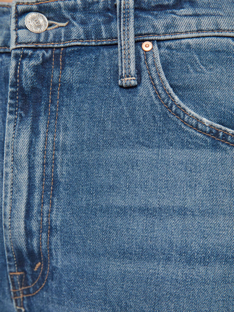 Close up swatch view of woman in a mid blue wash jean designed to sit lower on the hips with a loose straight leg and a 31-inch inseam with a clean cuffed hem.
