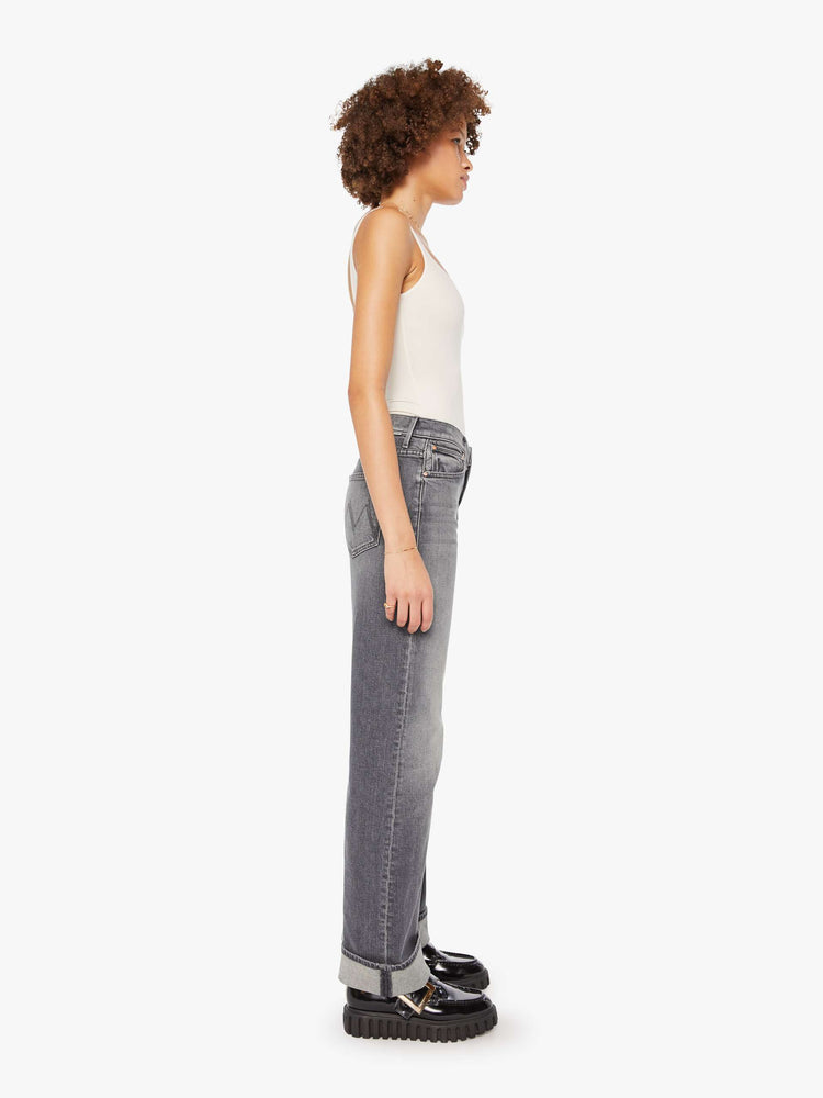 Side view of a woman in grey washed jeans designed to sit lower on the hips with a zip fly, loose wide leg and a 31-inch inseam with a cuffed hem.