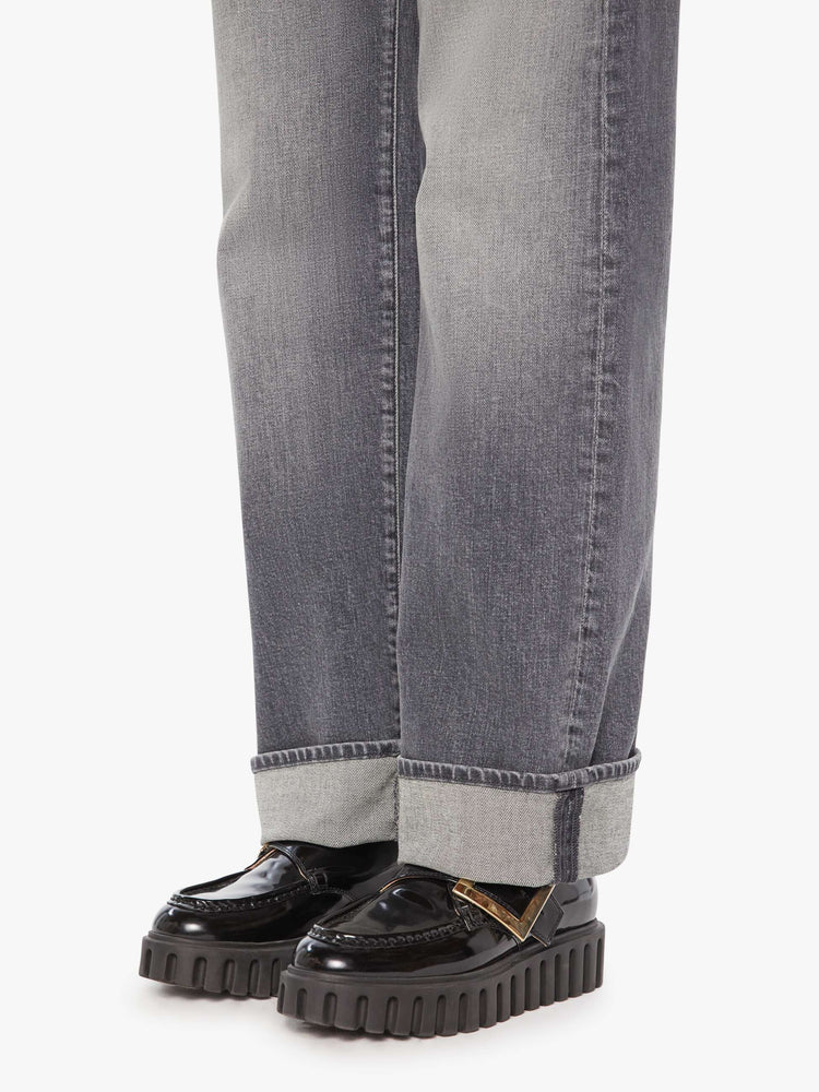 Hem view of a woman in grey washed jeans designed to sit lower on the hips with a zip fly, loose wide leg and a 31-inch inseam with a cuffed hem.