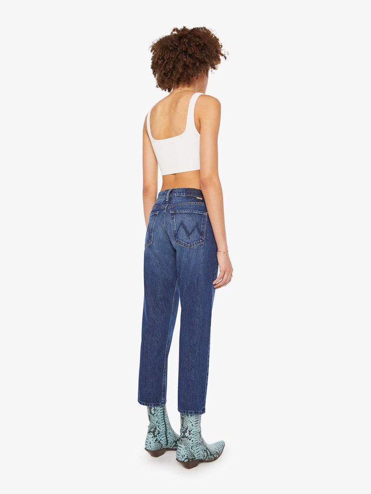 Back view of a woman in a dark blue  high-rise skinny-straight jeans have a zip fly, an ankle-length inseam and a clean hem. 