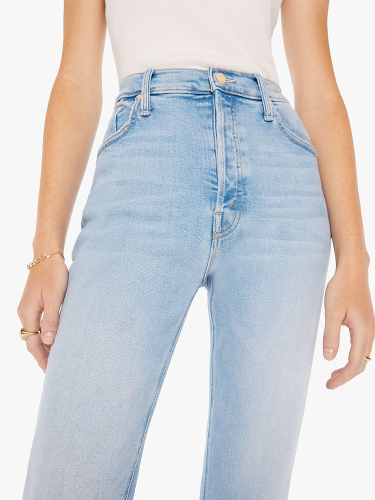 Waist close up view of a woman high-rise flare with a button fly and 28.25-inch inseam with a clean hem in a light blue wash.