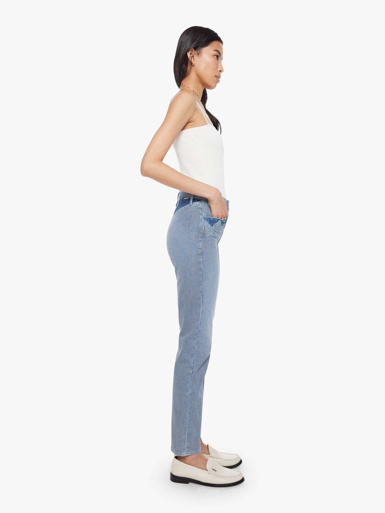 Side view of a woman in a midblue with white vertical stripes with high-rise jeans with a straight leg, zip fly, diamond cut-out details, an ankle-length inseam and a clean hem.