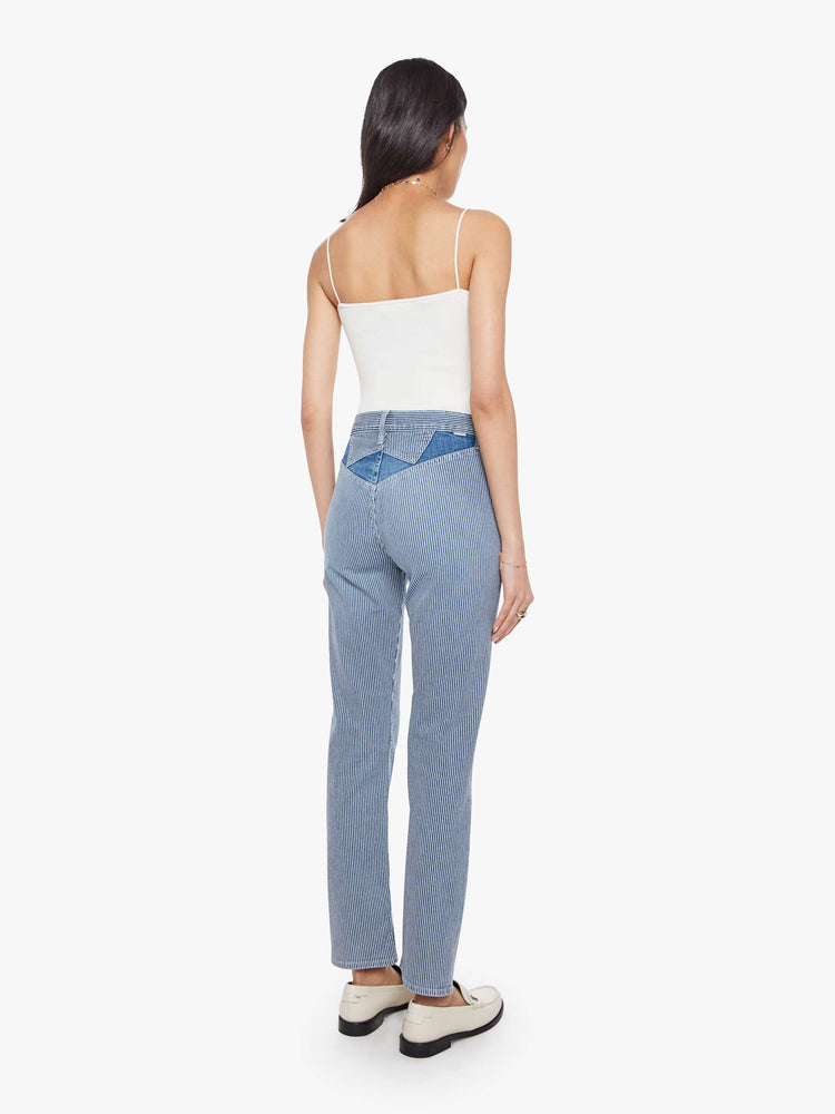 Back view of a woman in a midblue with white vertical stripes with high-rise jeans with a straight leg, zip fly, diamond cut-out details, an ankle-length inseam and a clean hem.