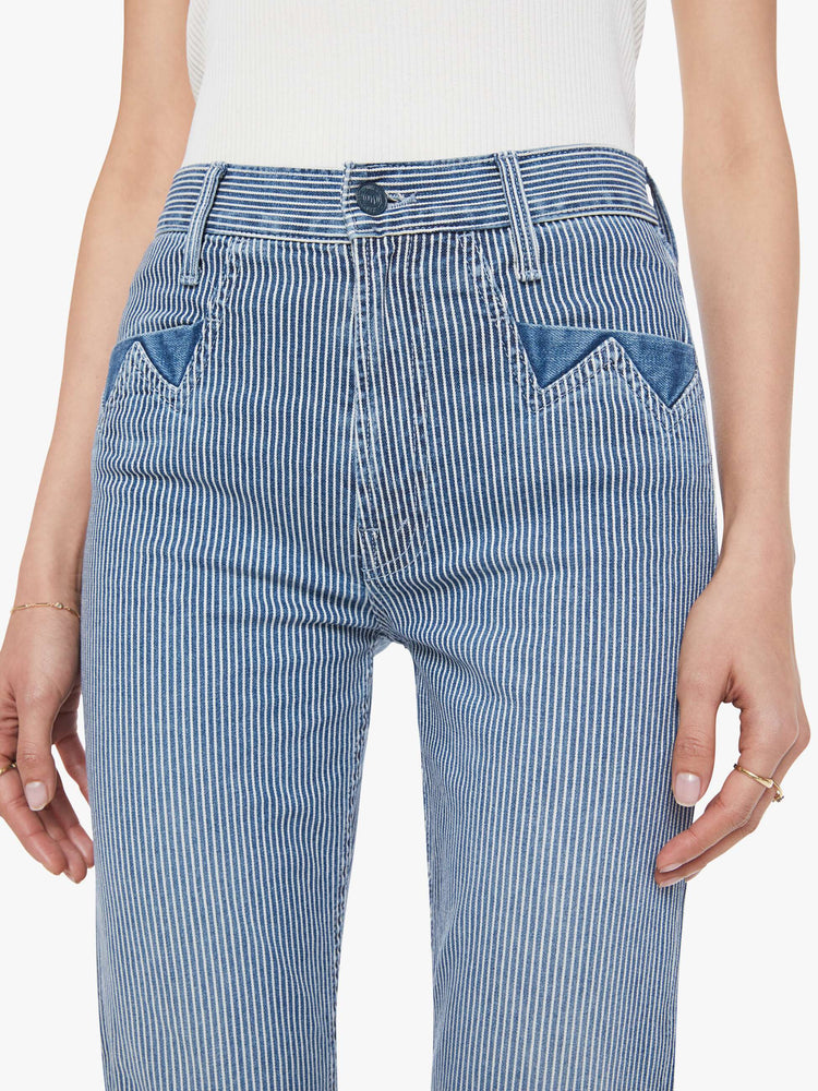 Close up view of a woman in a midblue with white vertical stripes with high-rise jeans with a straight leg, zip fly, diamond cut-out details, an ankle-length inseam and a clean hem.