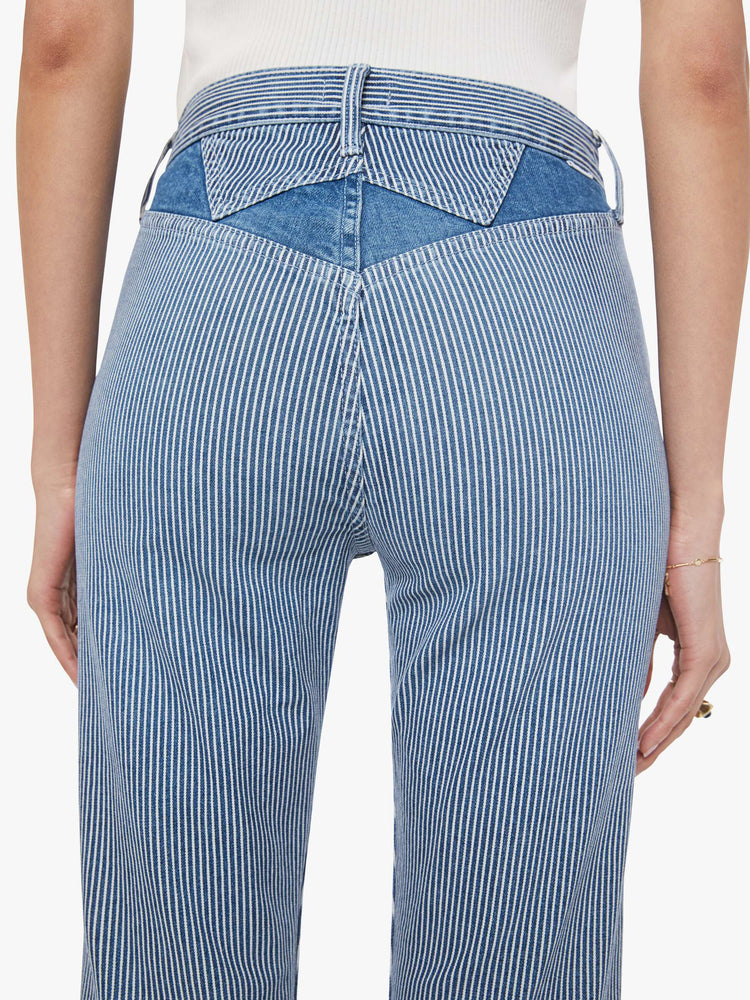 Back close up view of a woman in a midblue with white vertical stripes with high-rise jeans with a straight leg, zip fly, diamond cut-out details, an ankle-length inseam and a clean hem.