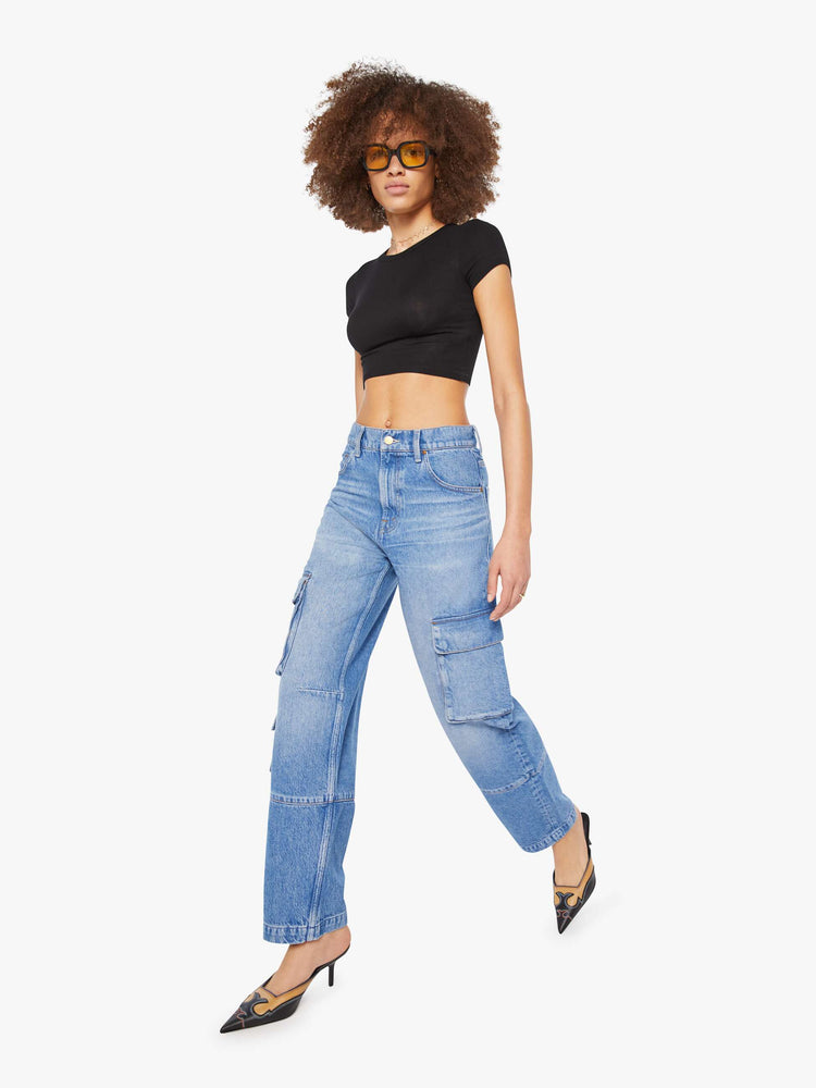 Walking view of a woman in a mid blue high-waisted jeans have a wide leg, zip fly, cargo-inspired patch pockets, a long 31-inch inseam and a clean hem.