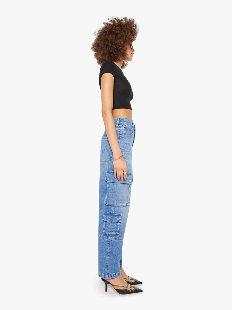 Side view of a woman in a mid blue high-waisted jeans have a wide leg, zip fly, cargo-inspired patch pockets, a long 31-inch inseam and a clean hem.