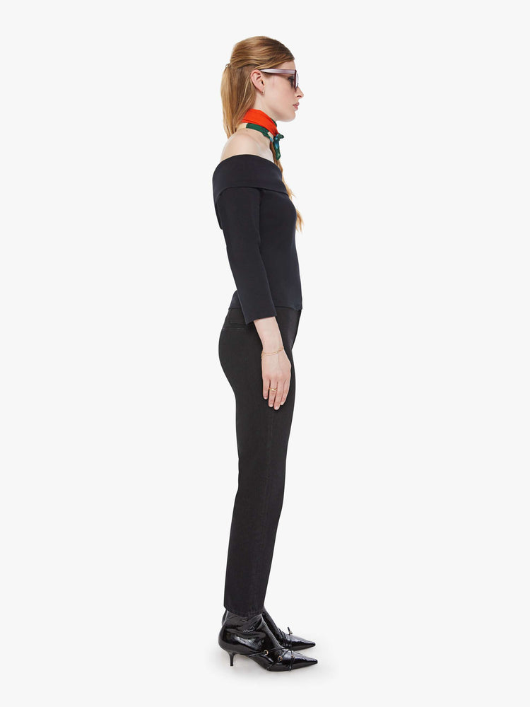 Side view of a woman in a black straight-leg jeans with a mid rise, zip fly, ankle-length inseam and a clean hem.