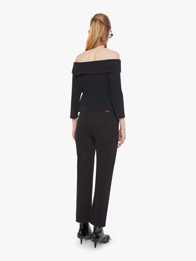 Back view of a woman in a black straight-leg jeans with a mid rise, zip fly, ankle-length inseam and a clean hem.