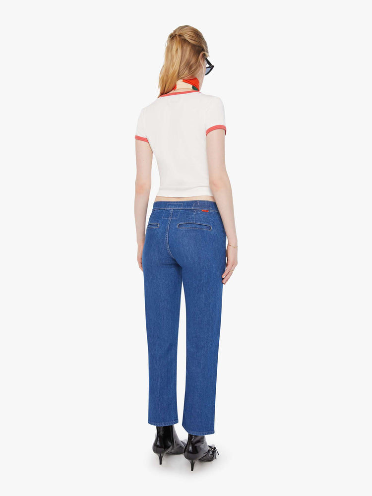 Back  view of a woman in a mid blue straight-leg jeans with a mid rise, zip fly, ankle-length inseam and a clean hem.