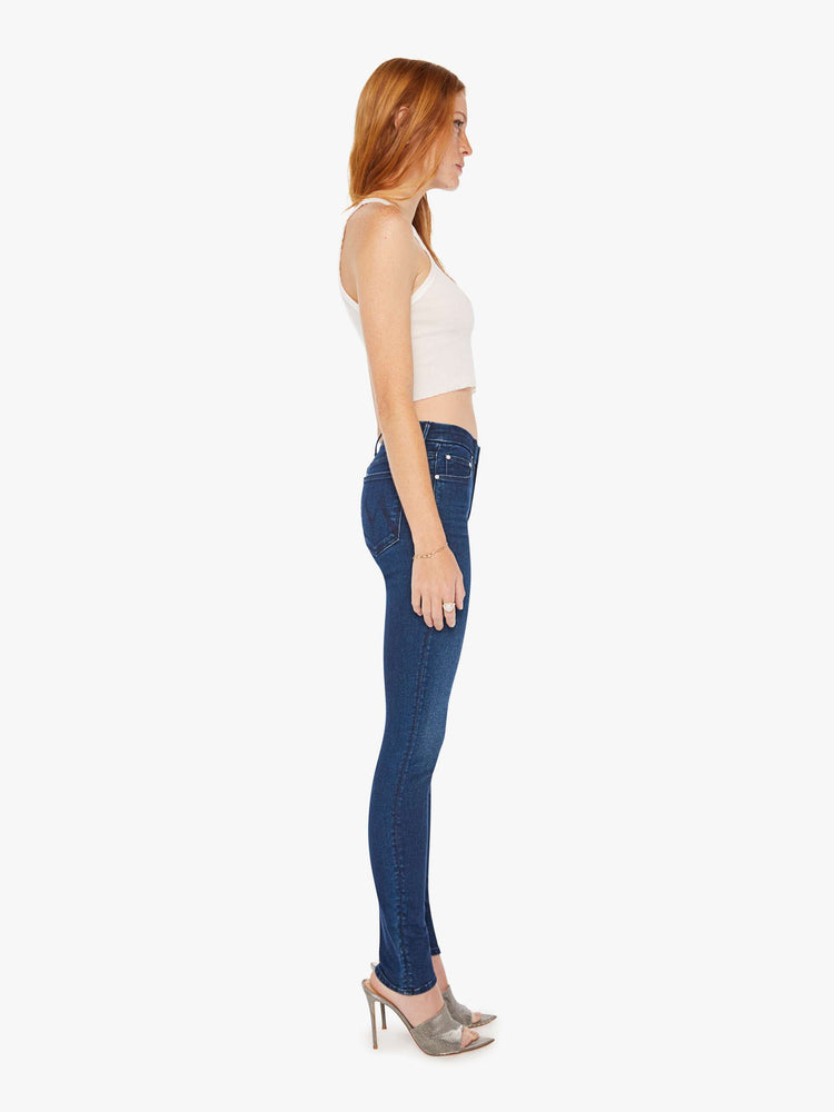 Side view of a woman cult-favorite skinny with a mid rise and a 31-inch inseam with a clean hem in a dark blue wash.