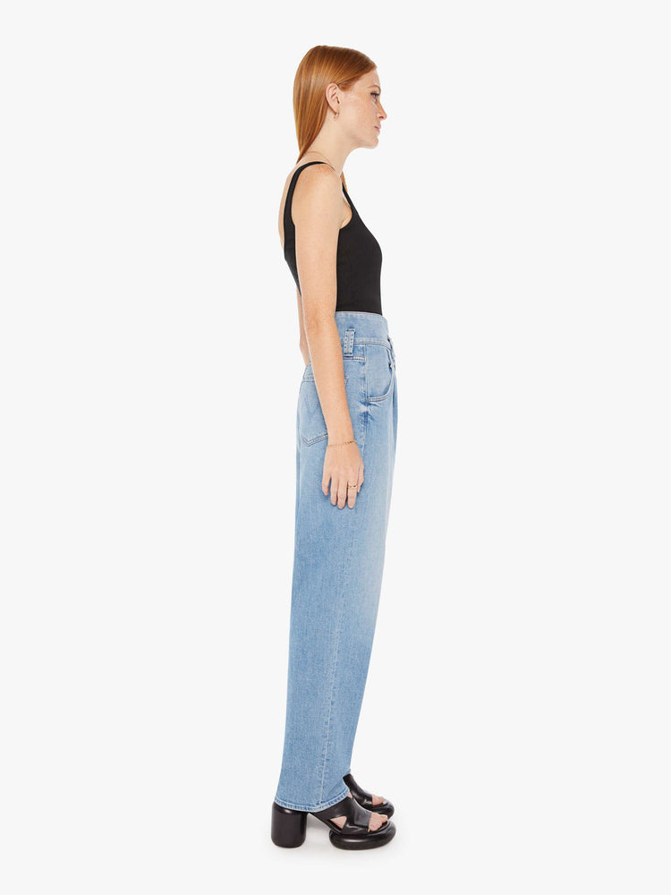 Side view of a womens light blue wash jean featuring a super high rise, a wide leg that tapers, and a button fly.