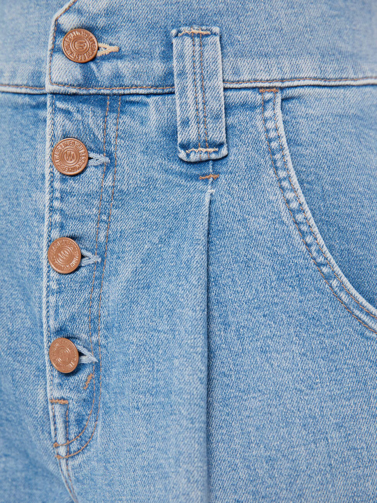 Close up swatch detail view of a light blue wash jean featuring a button fly.