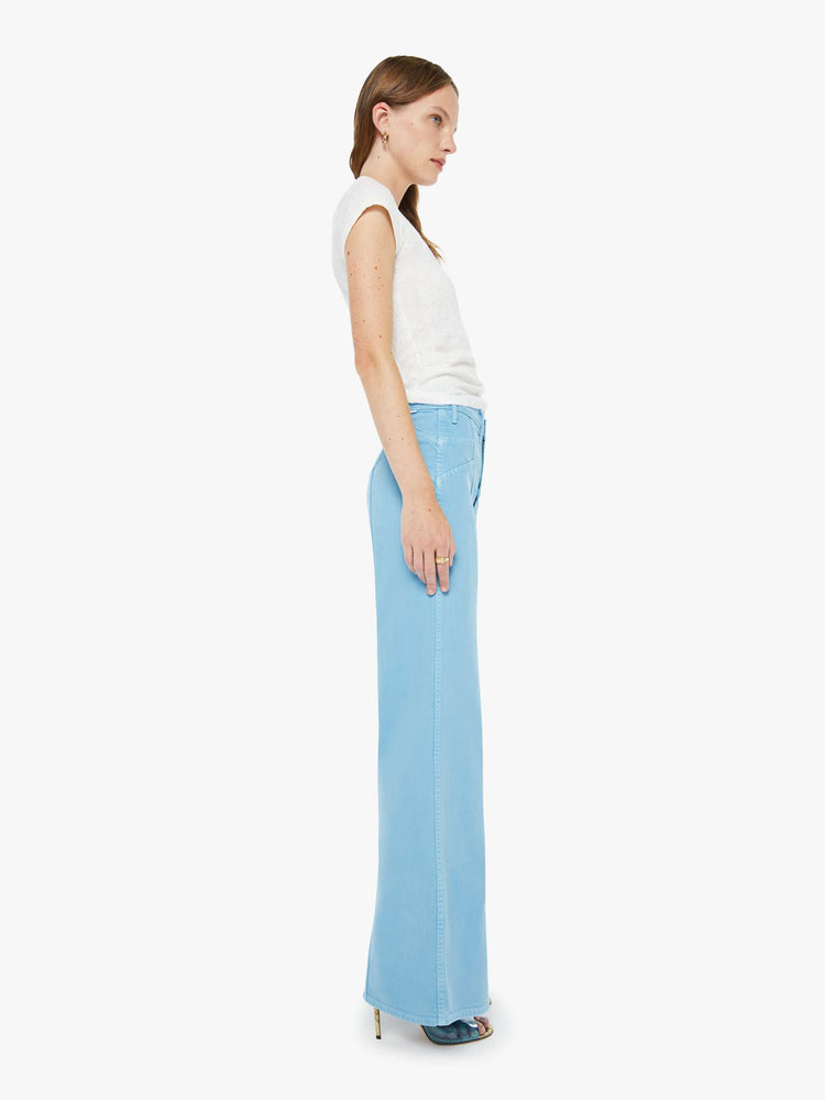 Side view of a woman in a light blue wide leg jeans with a high rise, zip fly, sun-shaped seamed details at the waist, a long 32-inch inseam and a clean hem.