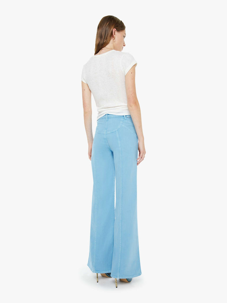 Back view of a woman in a light blue wide leg jeans with a high rise, zip fly, sun-shaped seamed details at the waist, a long 32-inch inseam and a clean hem.