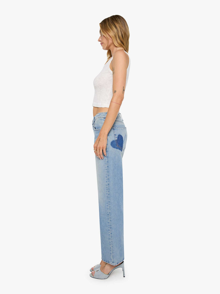 Side view of a woman  in a light blue mid-rise jeans with a wide straight leg, zip fly and long 32-inch inseam with a clean hem.