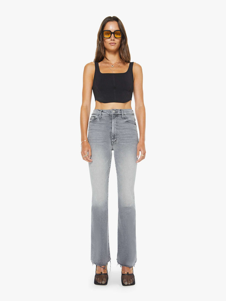 Front view of a woman in a light grey high-rise flare with a zip fly, 31-inch inseam and a frayed hem.