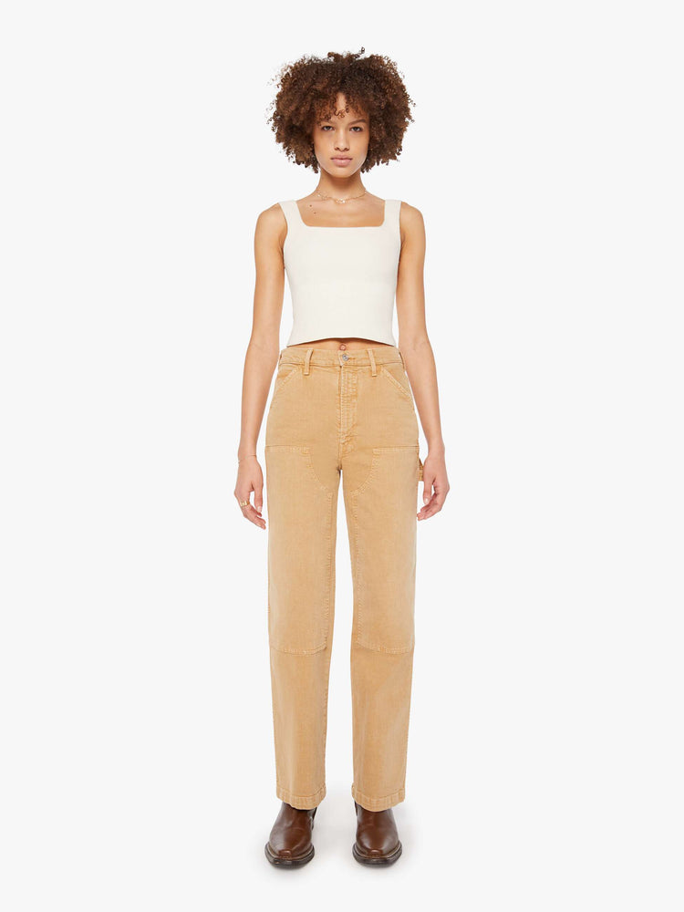 Front view of a woman in a faded khaki super high-waisted pants with a wide leg, zip fly, oversized patches at the knees, a long 32-inch inseam and a clean hem.