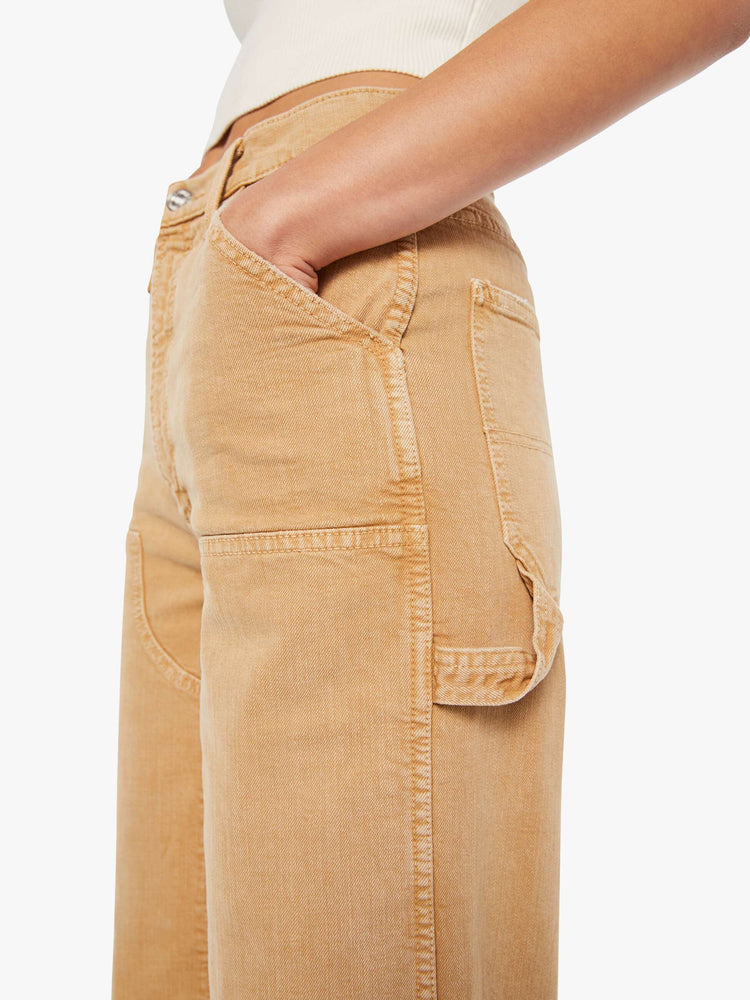 Close up view of a woman in a faded khaki super high-waisted pants with a wide leg, zip fly, oversized patches at the knees, a long 32-inch inseam and a clean hem.