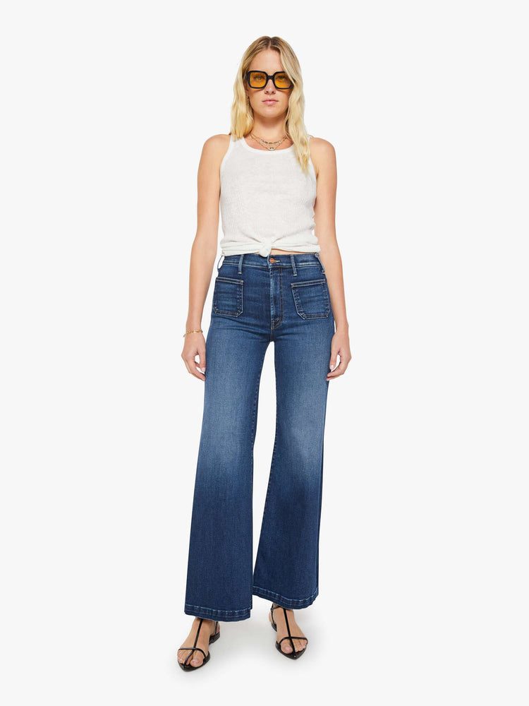 Front view of a woman in a dark blue wide leg jeans with a high rise, zip fly, patch pockets, 32-inch inseam and clean hem.