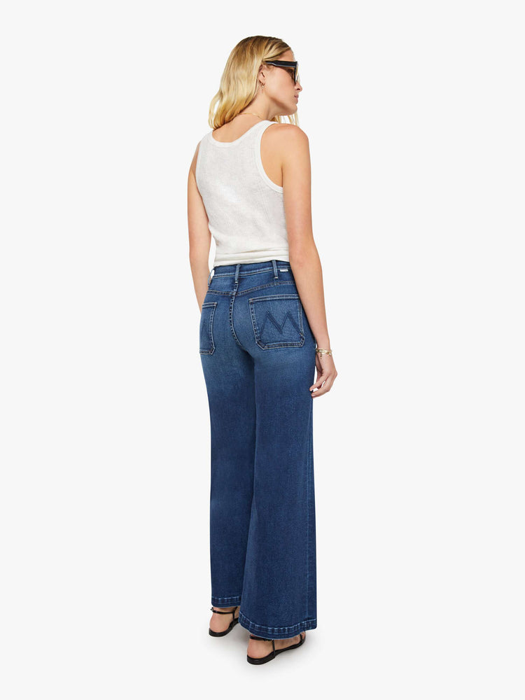 Back view of a woman in a dark blue wide leg jeans with a high rise, zip fly, patch pockets, 32-inch inseam and clean hem.