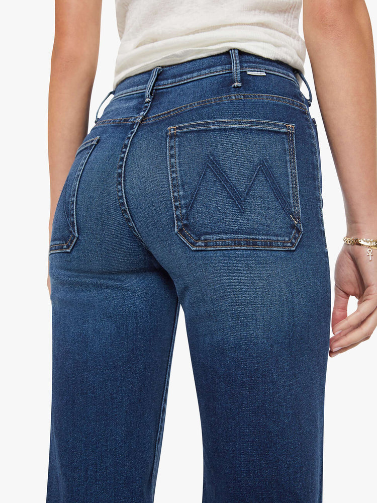 Close up view of a woman in a dark blue wide leg jeans with a high rise, zip fly, patch pockets, 32-inch inseam and clean hem.