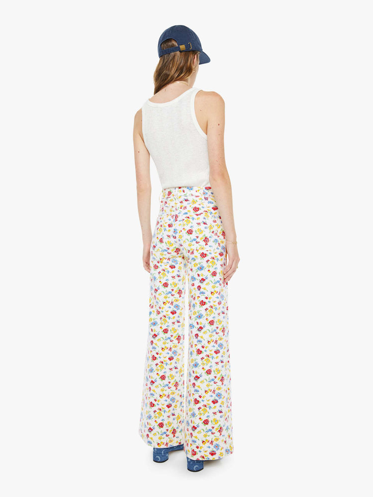 Back view of a woman in a bright white with colorful flowers wide leg jeans with a high rise, zip fly, patch pockets, 32-inch inseam and clean hem. 
