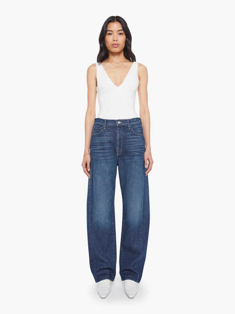 Front view of a woman in a dark blue jeans designed to sit lower on the hips with a wide, full barrel leg, zip fly, a long 31-inch inseam and a clean hem.