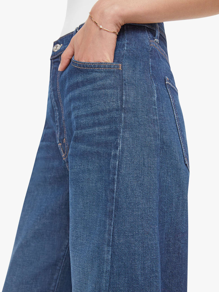 Close up view of a woman in a dark blue jeans designed to sit lower on the hips with a wide, full barrel leg, zip fly, a long 31-inch inseam and a clean hem.