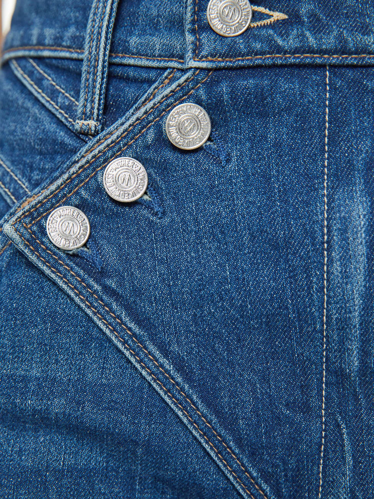 Swatch view of a woman in a mid blue super high-rise straight-leg jeans with a buttoned flap at the waistband, angled seamed details and a 29-inch inseam with a clean hem.