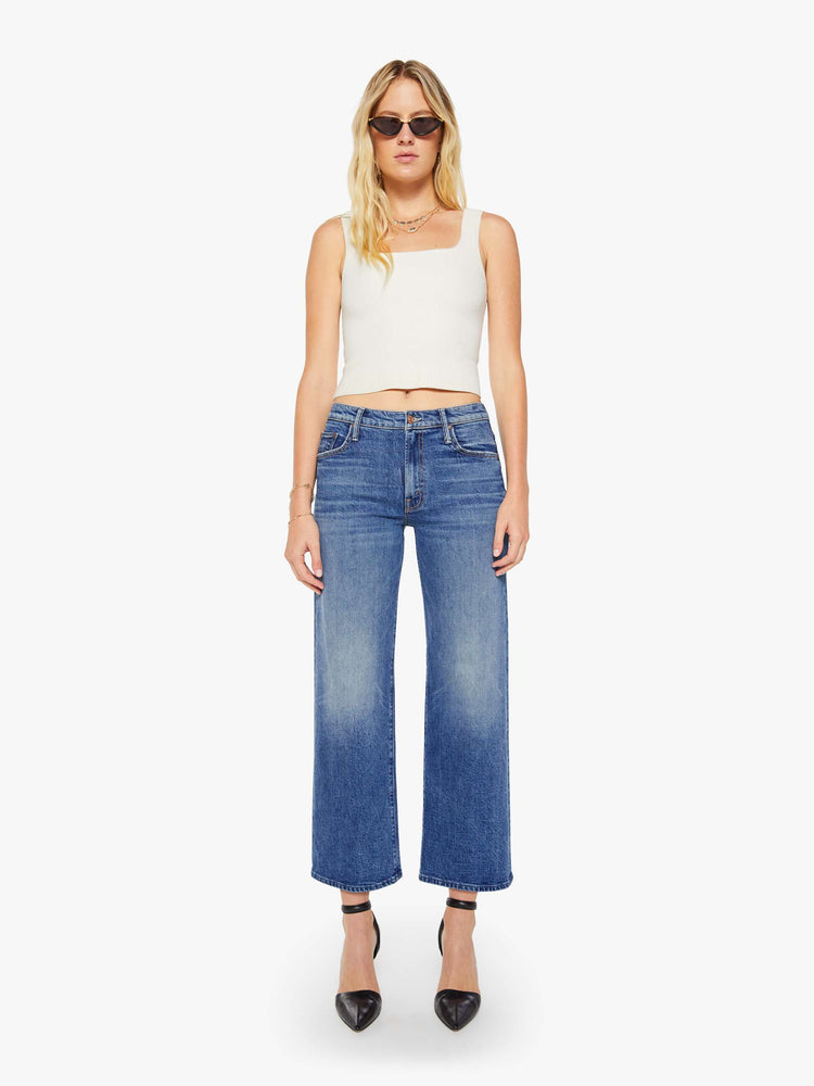 Front view of a woman in a med blue mid-rise jeans with a loose fit, wide leg, zip fly and a 28.25-inch inseam with a clean hem.