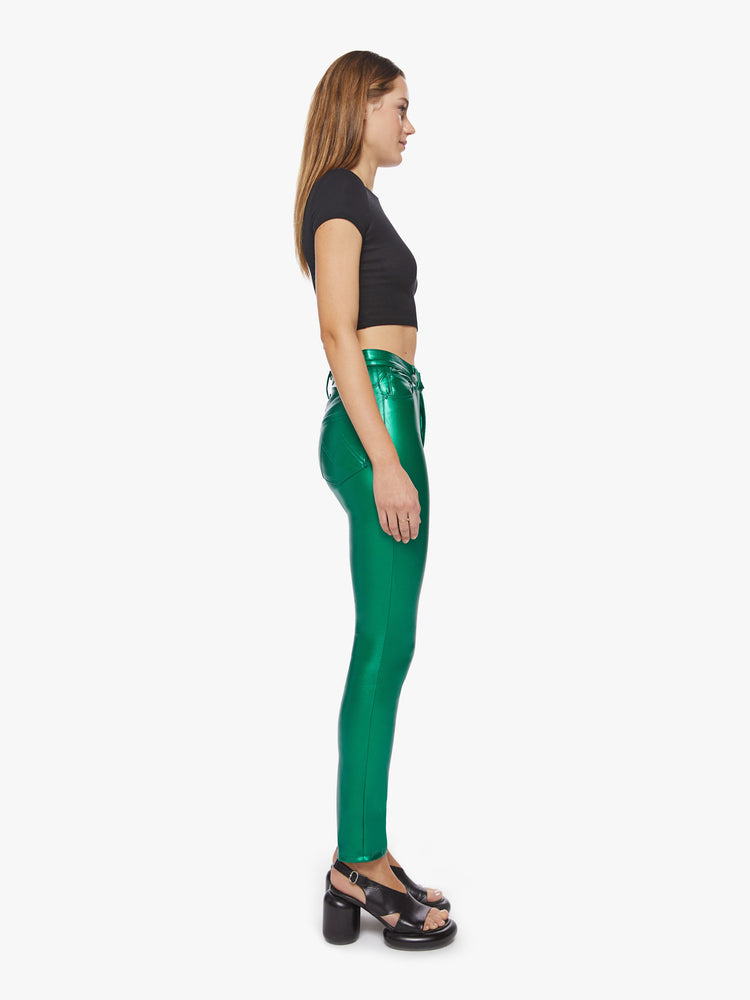 Side view of a woman super high-waisted faux leather green skinny-leg pants with a 31-inch inseam and a clean hem.